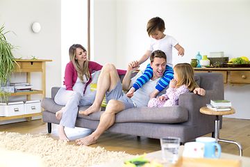 Nelihenkinen perhe olohuoneessa, jossa Airthings WavePlus seinällä heidän takanaan