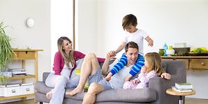 Nelihenkinen perhe olohuoneessa, jossa Airthings WavePlus seinällä heidän takanaan