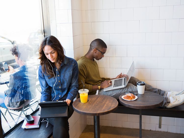 Kaksi henkilö kahvilassa kannettavien tietokoneiden kanssa