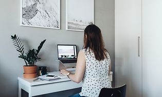 Nainen istuu kotitoimistossaan työskentelemässä tietokoneella