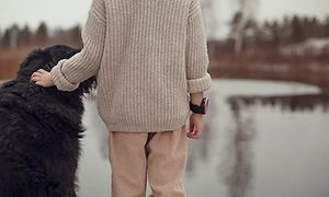 Lapsi Xplora X5 -älykello yllään silittää koiraa