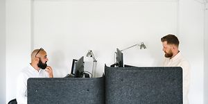Kaksi miestä istuu työpisteillään toimistossa ja työskentelevät tietokoneillaan