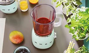 Vastavalmistettu smoothie ja Smegin 50-luvuntyylinen retro pastellinsininen tehosekoitin keittiön työtasolla