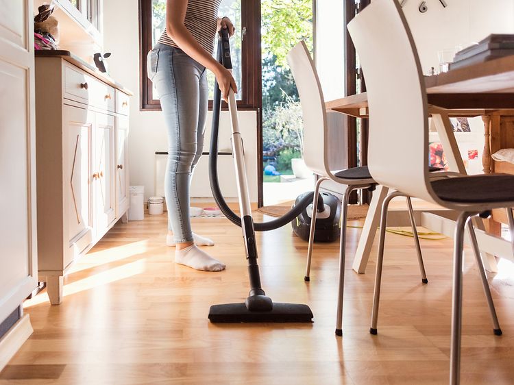 Woman using the vacuum cleaner in the kitchen