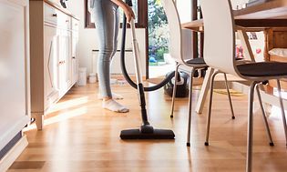 Woman using the vacuum cleaner in the kitchen