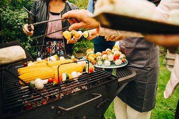 People standing around a charcoal grill grilling vegstables