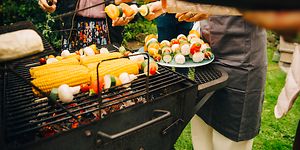 People standing around a charcoal grill grilling vegstables