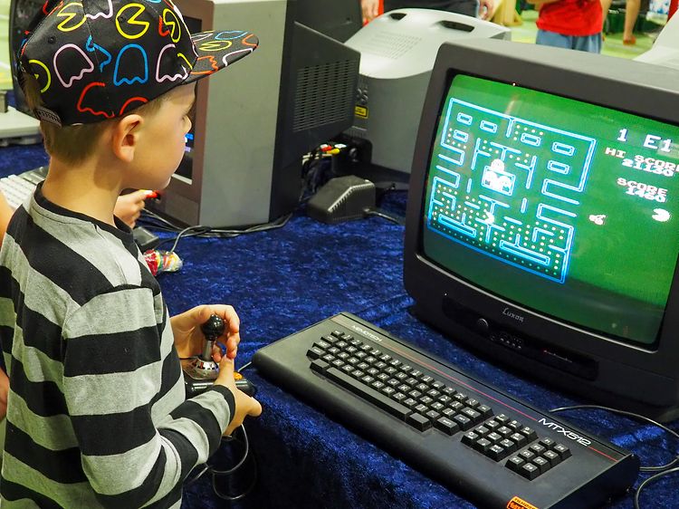 Poika pelaamassa alkuperäistä PacMan-peliä kuvaputkitelevisiolla.