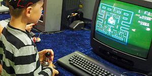 Poika pelaamassa alkuperäistä PacMan-peliä kuvaputkitelevisiolla.
