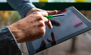 Miehen kädet, vihreä kynä ja iPad-laite