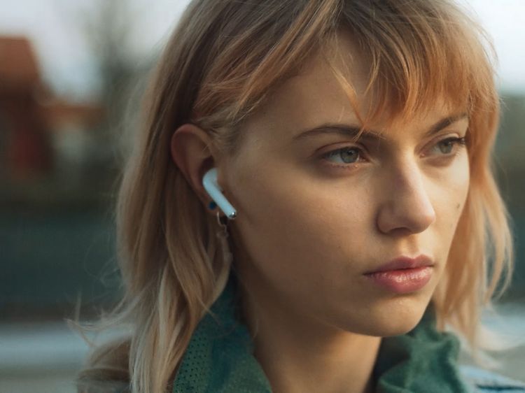 Nuori nainen ulkona AirPods-kuulokkeet korvissaan