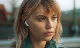 Nuori nainen ulkona AirPods-kuulokkeet korvissaan