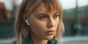 Nuori nainen ulkona AirPods-kuulokkeet korvissaan
