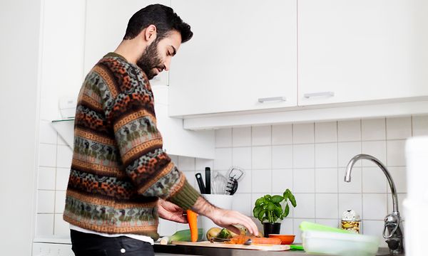 Mies laittaa ruokaa keittiössä
