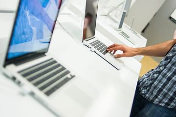 Henkilö tutustuu kannettavaan tietokoneeseen kaupassa