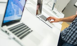 Henkilö tutustuu kannettavaan tietokoneeseen kaupassa