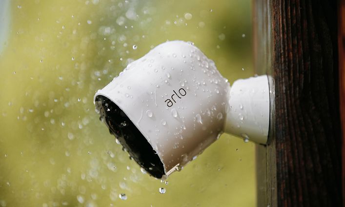Valkoinen Arlo Pro 3 seinällä vesisateessa.