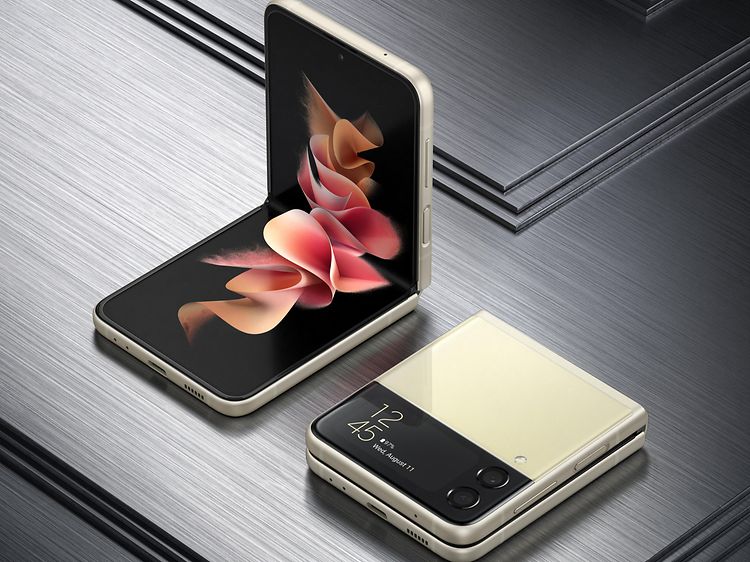 Kaksi beigeä Samsung Galaxy Z Flip3 -puhelinta harmaalla taustalla