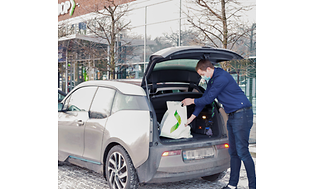 Gigantin työntekijä asettaa asiakkaan tilaamia tuotteitan hänen autonsa takakonttiin