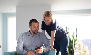 Mies ja nainen katsovat älypuhelinta