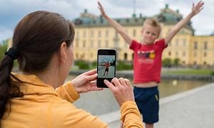 Nainen käyttää älypuhelinta pojan kuvaamiseen