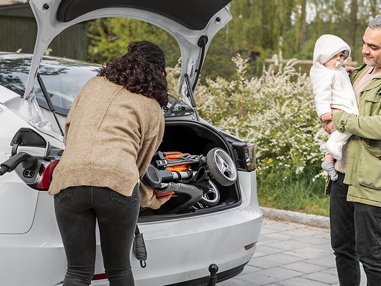 Perhe pakkaa sähköautoa joka on latauksessa