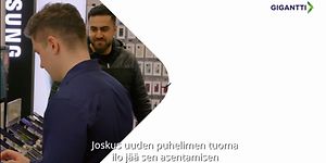 Kuvakaappaus älypuhelinten suojaamesta kertovasta videosta jossa kaksi miestä Gigantti-myymälän puheliosastolla