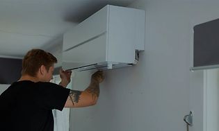 Mies asentaa ilmalämpöpumppua