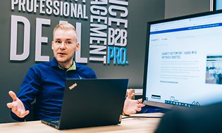 Yritysmyyjä ja asiakas pöydän ääressä keskustelemassa, taustalla näyttö ja gigantin verkkosivut