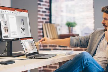 Mies puhuu puhelimeen ja työskentelee samalla Lenovo-kannettavallaan
