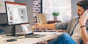 Mies puhuu puhelimeen ja työskentelee samalla Lenovo-kannettavallaan