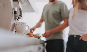 A coffee machine and a couple standing in the background