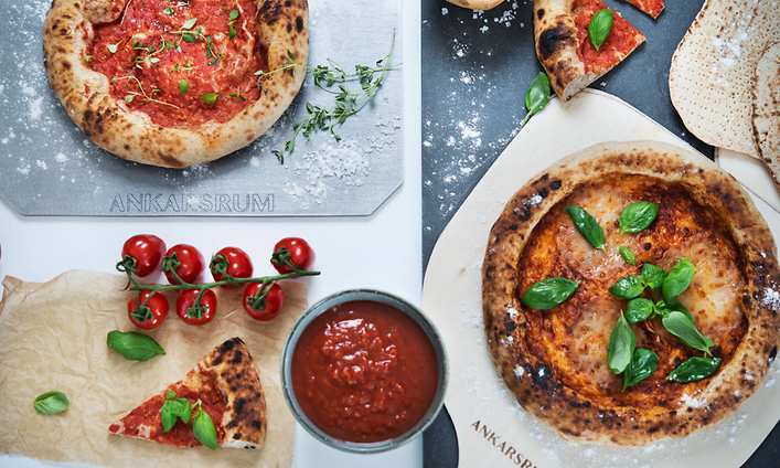 erilaisia pizzoja ja pizzatäytteitä pizzanrpaistoalustalla ja pizzakivellä