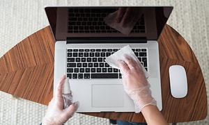 Tietokoneet - Korjaus - Henkilö puhdistaa kannettavaa tietokonetta talouspaperilla
