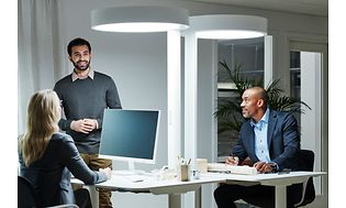 Työntekijät juttelevat toimistossa, jossa pöydällä BrainLit-valaisin heidän vieressään