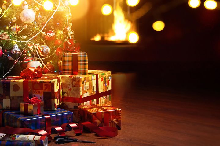 Christmas tree and presents under the tree and a fireplace in the background