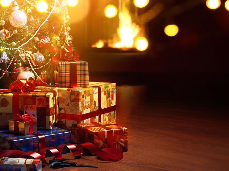 Christmas tree and presents under the tree and a fireplace in the background