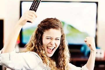 TV - Asennus - nainen iloitsee  television edessä kaukosäädin kädessään
