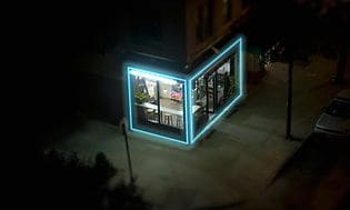 Lintuperspektiivistä kuvattu pieni kahvila, joka on valaistu kirkkaalla sinisellä LED-valolla