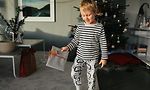 Yöpukuun pukeutunut poika pitelee joululahjaa kädessään