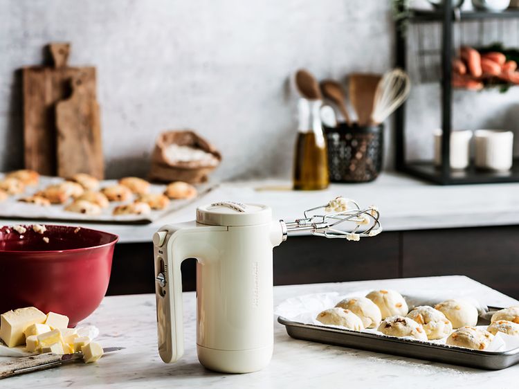 Kermanvärinen KitchenAid sähkövatkain, jonka vieressä on leivonnaisia