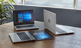 Kolme HP EliteBook-kannettavaa toimiston pöydällä