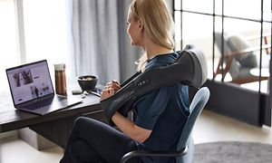 Tietokoneella työskentelevä nainen hieroo hartioita RE-hierontatuotteella