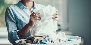 Nainen viikkaa pyykkikorista nostamaansa pyykkiä
