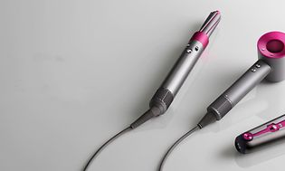 Kolme erilaista Dyson-hiustenmuotoilulaitetta vierekkäin sekä Dyson-logo