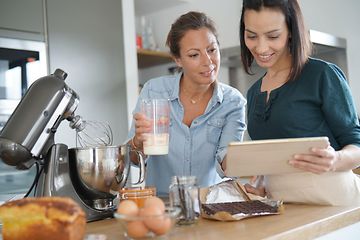 Kaksi naista käyttää yleiskonetta leipomiseen