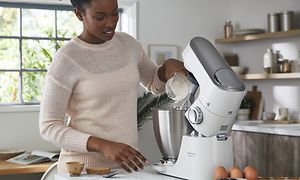 Nainen nostaa Titanium Chef Baker Lite -yleiskoneen yläosaa