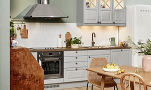 Vaalean harmaa EPOQ Heritage -keittiö avokeittiöratkaisulla sekä ruokailuryhmä, liesituuletin ja jääkaappi