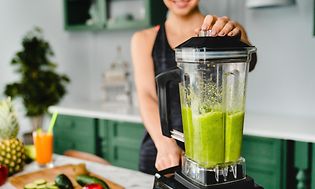 Nainen tekee vihreää smoothieta tehosekoittimella