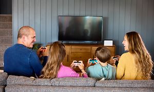Nelihenkinen perhe pelaa Nintendo Switchiä sohvalla